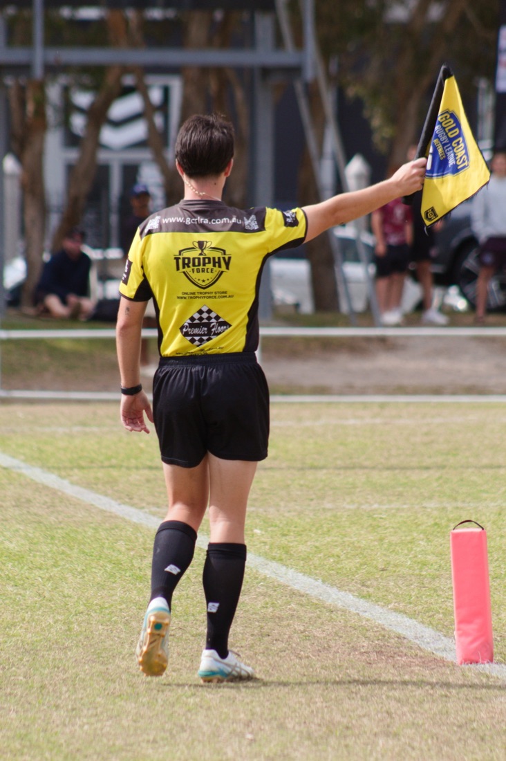A Gold Coast touch judge raising the flag on the sideline